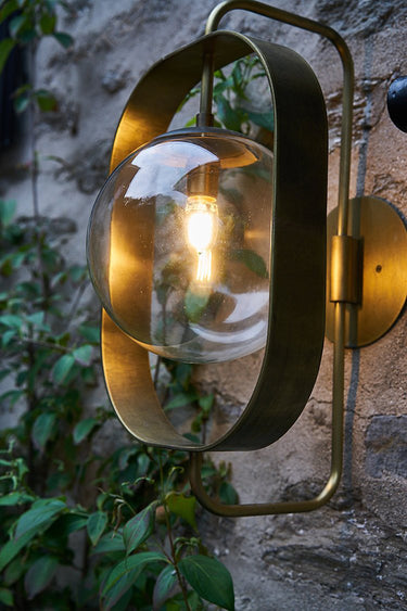 Robert True Ogden RTO Lighting - Olivia Wall Sconce - Brushed Satin Brass - Clear Glass Globe Outdoors on a Brick Wall#finish_brushed-satin-brass #globe_clear-glass #location_outdoor