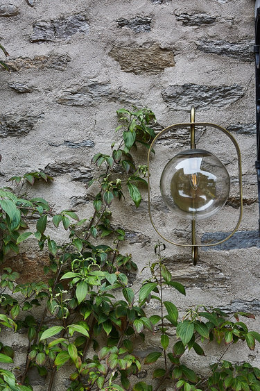Robert True Ogden RTO Lighting - Olivia Wall Sconce - Brushed Satin Brass - Clear Glass Globe Outdoors on a Brick Wall#finish_brushed-satin-brass #globe_clear-glass #location_outdoor