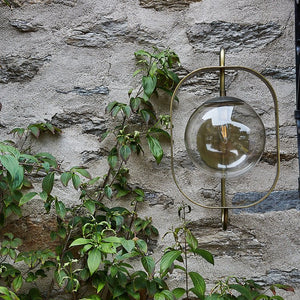Robert True Ogden RTO Lighting - Olivia Wall Sconce - Brushed Satin Brass - Clear Glass Globe Outdoors on a Brick Wall#finish_brushed-satin-brass